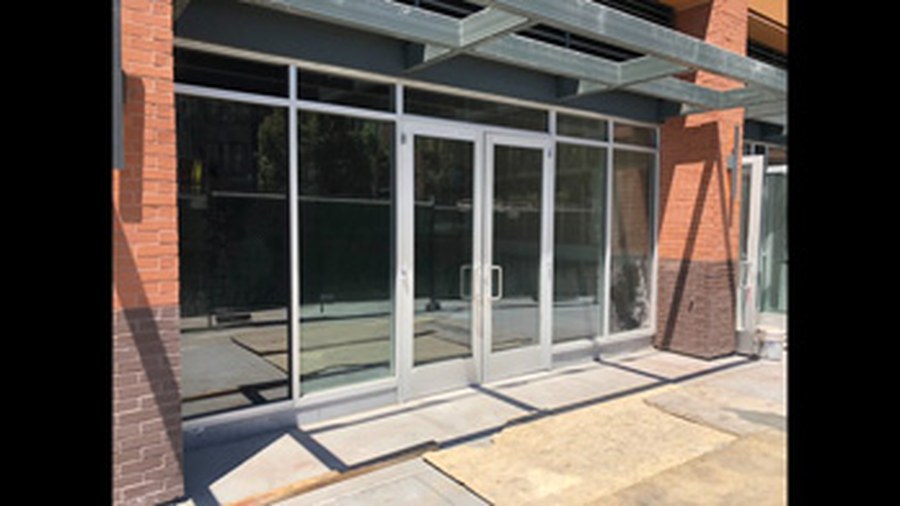 Double glass entry doors with tall sidelights under a metal canopy
